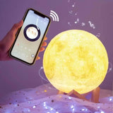 Lampa oblikovana kao Mesec prikazana uz postolje od drveta.