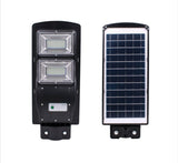 Na slici je solarni LED reflektor od 60 W za stubnu montažu, uz daljinski upravljač.