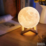 Reljefna 3D lampa u obliku Meseca prikazana na drvenom postolju.